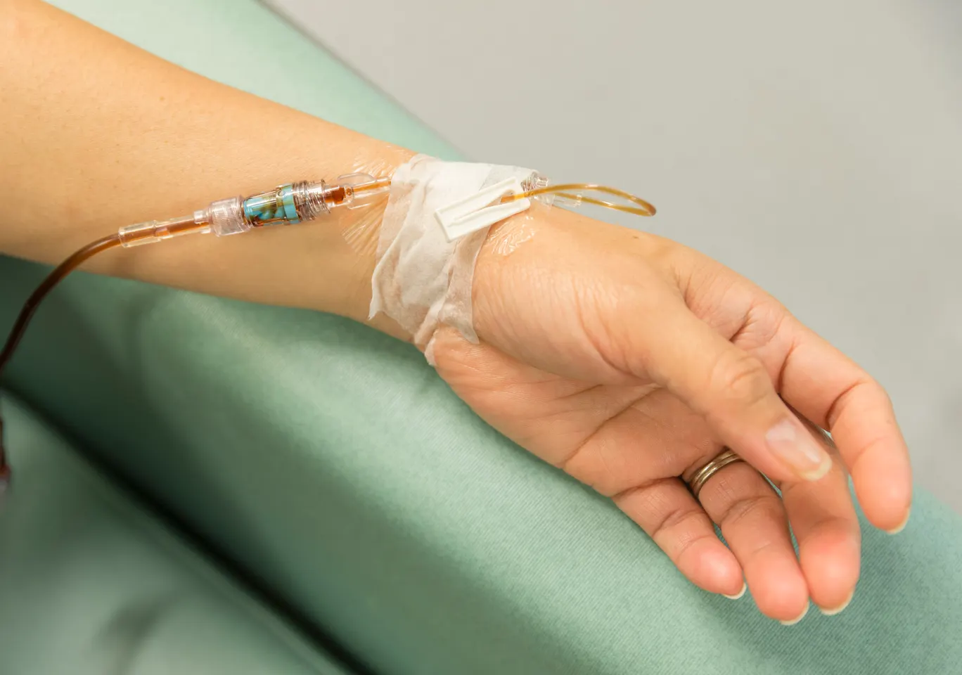 Kroplówki witaminowe Kartuzy: dłoń z wenflonem i linią infuzyjną na podkładzie